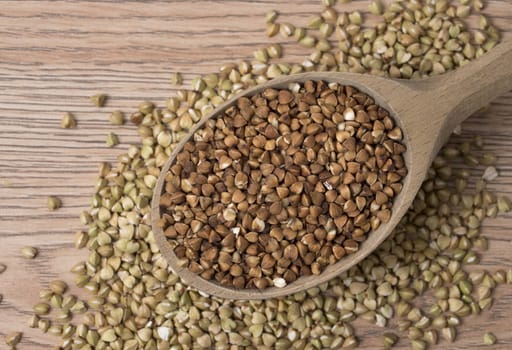 Natural fresh buckwheat in wooden spoon. On a wooden table. Top view.