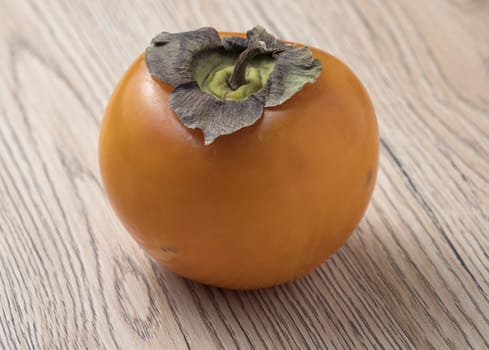 Whole ripe persimmon fruit on wooden background. Close up view.
