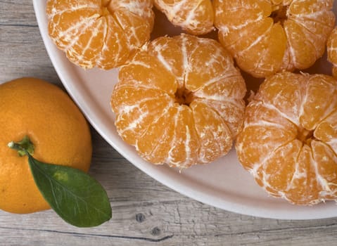 Fresh ripe peeled tangerine in a dish on a wooden background.  Close up view.