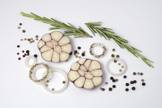 Food background of onion rings, peppercorns, rosemary and garlic cloves, on white. Overhead view.