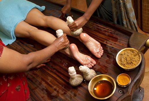   indian doctors doing traditional ayurvedic oil foot massage