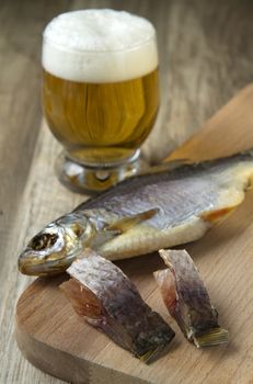 salt dried fish and glass of beer on wooden background