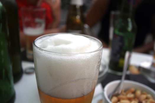 table with aperitif and snack bar, close up on glass of beer