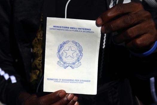 Caserta, Italy - September 27, 2019: A migrant shows his residence permit for foreigners