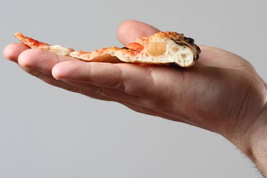 close up on the hand holding the slice of sliced pizza