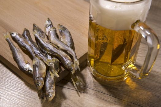 Beer mug and dried fish on wooden table.