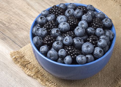 Forest berries (blueberry,bramble) in a ceramic blue  bowl. Top view.