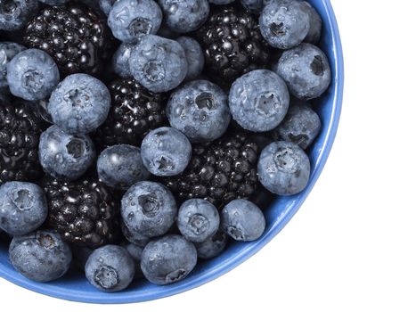 Bowl full of fresh blackberries and blueberries on white background.