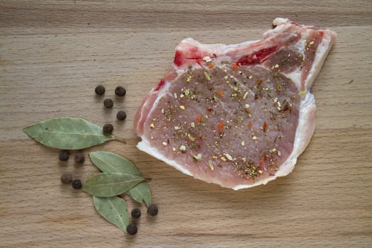 raw pork chop on a cutting board with spices