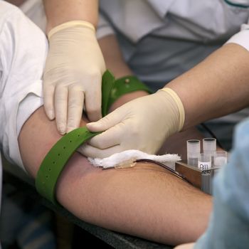   blood donation, hands with rubber tourniquet used in blood draw procedures.