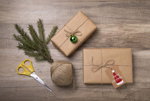 Christmas or New Year gift boxes wrapped in kraft paper with blank gift tag on old wooden background.