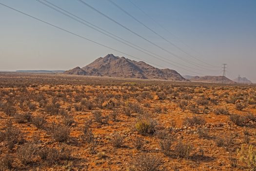 High voltage power lines in the lonely Kalahari desert indicating life and industry in this barren landscape.