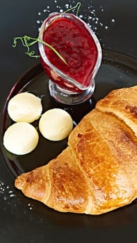 Closeup of butter, jam and fresh croissants.