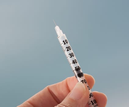 closeup on a female hand holding an insulin subcutaneous needle 