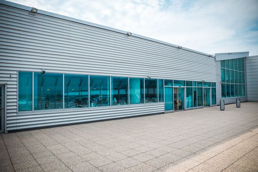 Exterior of a modern steel and green glass office building with empty walkway. panoramic and perspective view.