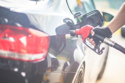 Pumping gas at gas pump. Closeup of man pumping gasoline fuel in car at gas station.