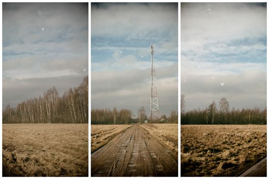 view of the communications tower and road to the forest, against a blue sky with white clouds