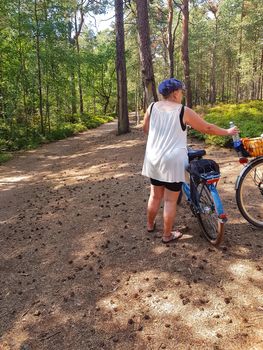 Woman with bicycle enjoys summer holidays on the Baltic Sea on the way to the lighthouse in Prerow.