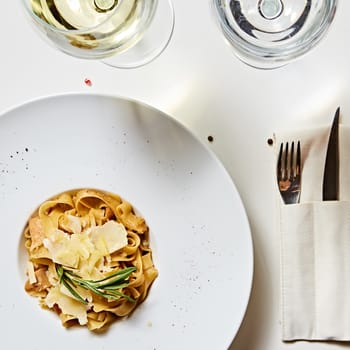 Close-up italian pasta plate with grated parmesan cheese and basil leaf.