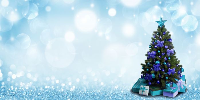 Fully decorated christmas tree with blue and green baubles and bows and presents on glitter bokeh background