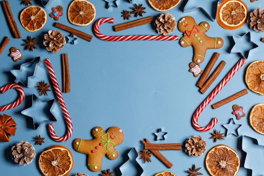Christmas food frame. Gingerbread cookies, spices and decorations on blue background with copy space