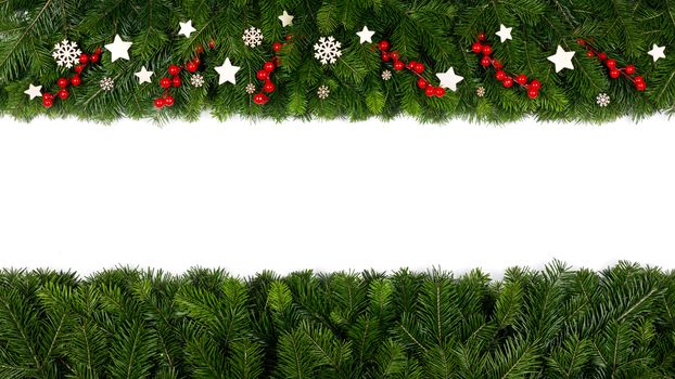 Christmas Border frame of tree branches and red berries and wooden decor on white background with copy space isolated