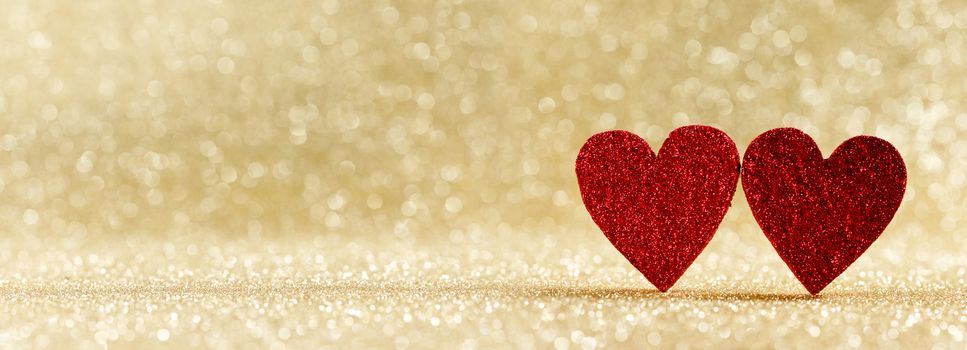 Two red wooden hearts on golden glowing bokeh hearts background for Valentines day