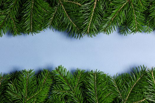 Natural fir Christmas tree border frame on blue, copy space for text