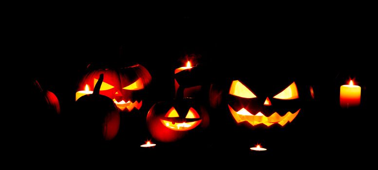 Halloween pumpkins head jack o lantern and fire of candles on wooden background