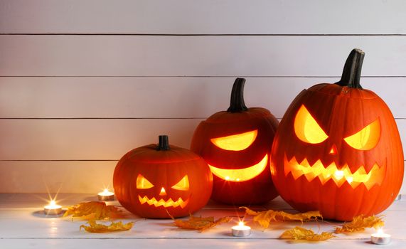 Halloween pumpkin head jack o lantern and candles on wooden background