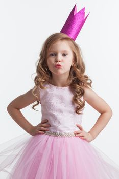 Little princess girl in pink dress and crown giving a kiss , studio isolated on white background