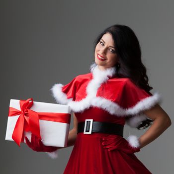 Smiling cute girl in red christmas outfit holding gift box
