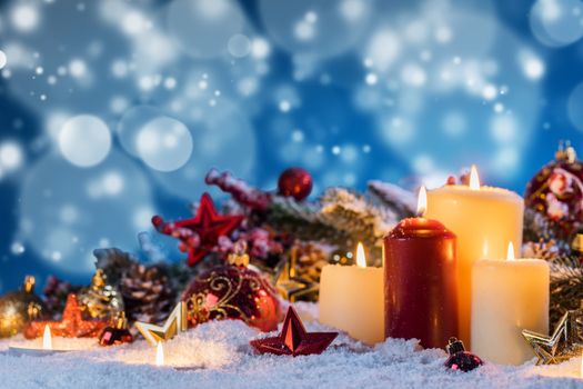 Christmas candles with traditional decorative stars , red baubles , pine cones and green branches on snow