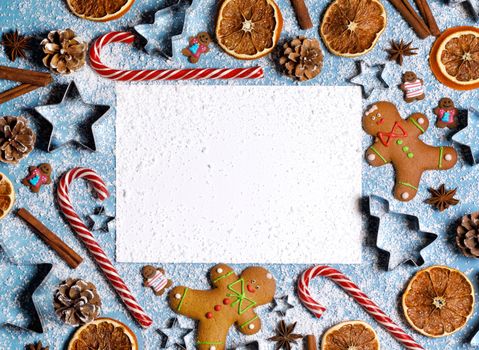 Christmas food frame. Gingerbread cookies, spices and decorations on blue background with copy space on blank card