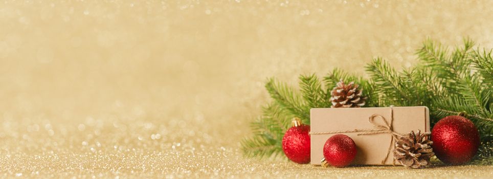 Christmas toys, decorations, present gift box wrapped in kraft paper on golden glitter background, copy space