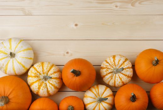 Many orange pumpkins on light wooden background, Halloween concept, top view with copy space