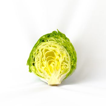 Close-up view of a half cut fresh green iceberg lettuce saladisolated on white background.Organic food background with copyspace.
