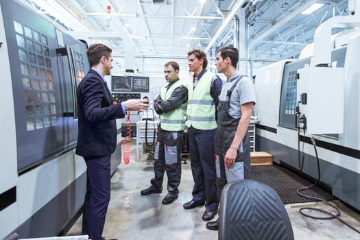 Manager and workers at plant near CNC machines