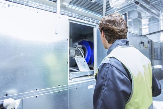 Worker in electrical switchgear room of CNC plant