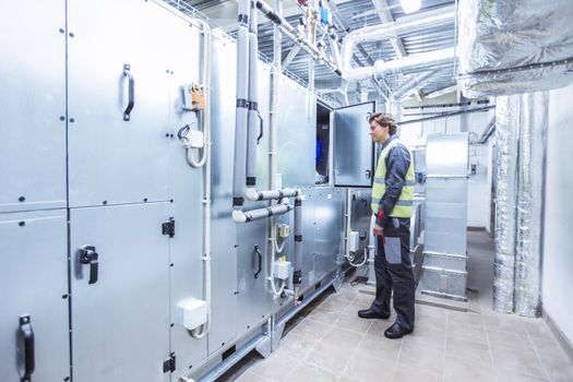 Worker in electrical switchgear room of CNC plant