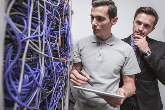 Young engeneer and manager in network server room with digital tablet