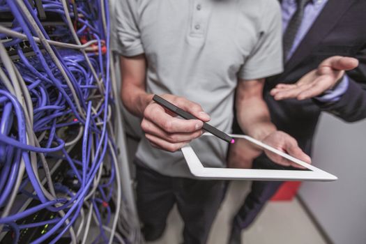 Young engeneer and manager in network server room with digital tablet