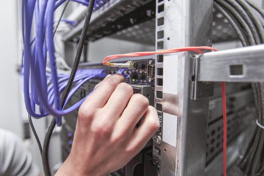 Young engeneer man in network server room checking rack devices