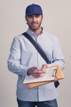 Man in blue uniform holding delivery form on clipboard for delivery