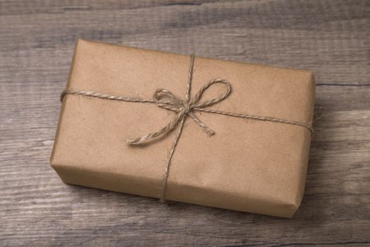 Christmas or New Year gift box wrapped in kraft paper on old wooden background.
