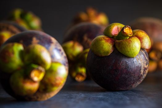 Mangosteen fruit on black cement floor and morning light. Is a seasonal fruit in Thailand. Closeup and copy space for text.