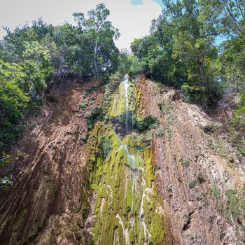 Close up of the wonderful El Limon tropical waterfall with lots of moss and steaming water, seen from below the waterfall in the Dominican Republic of the Samaná peninsula.