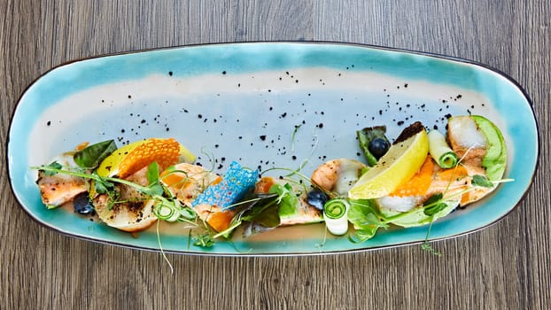 fried fish rolls with herbs and vegetables on blue plate