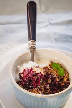 baked oat-blueberry crumble with mint in a white and blue plate on a rustic linen tablecloth. Save the space, top view. The concept of healthy proper nutrition for breakfast, vegetarianism