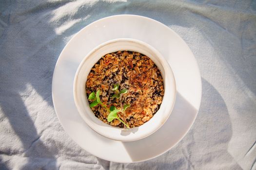 baked oat-blueberry crumble with mint in a white and blue plate on a rustic linen tablecloth. Save the space, top view. The concept of healthy proper nutrition for breakfast, vegetarianism